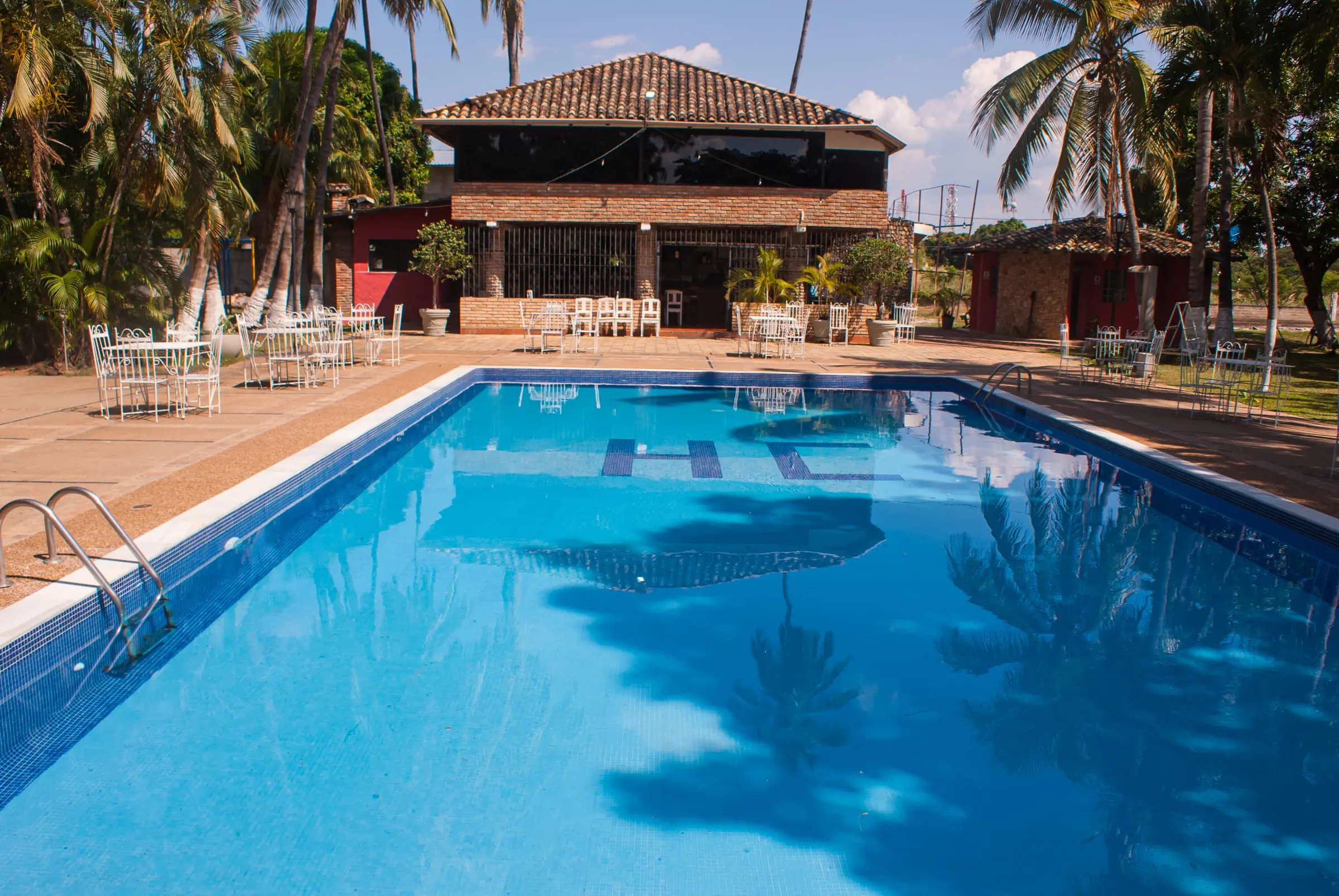 Piscina del Hotel Cacique rodeada de palmeras, hotel en Barinas, Venezuela